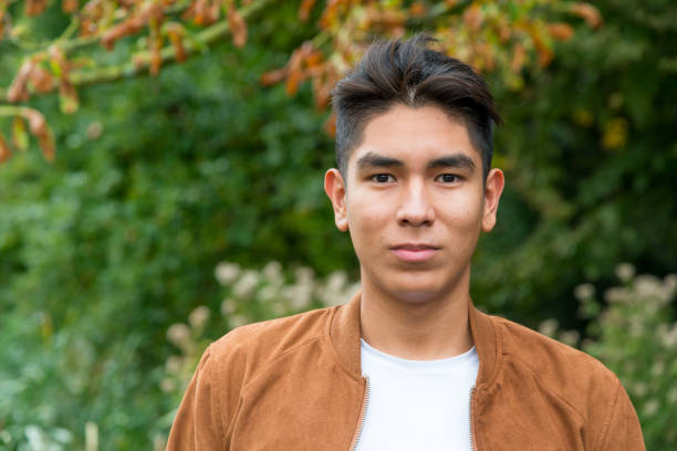 Portrait of a smiling  Latin American young man with a brown suede jacket, shot outside